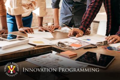 VMI Innovation Programming - A group of people work at a table with charts, graphs, and paperwork.