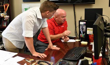 A man and a student look at a computer