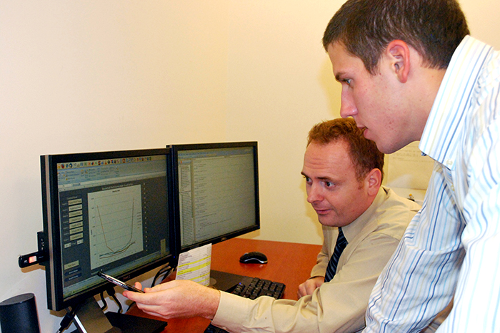 A man points at a computer while a student looks on