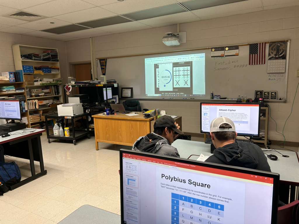 Students in the high school classroom working on ciphers and puzzles at computers.