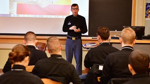 A cadet stands in front of a class