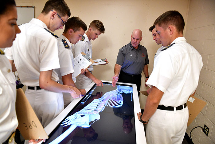 Col. Mike Krakow and a group of cadets stand around an anatomage table