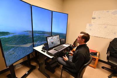 A student sits in front of a simulated plane flight