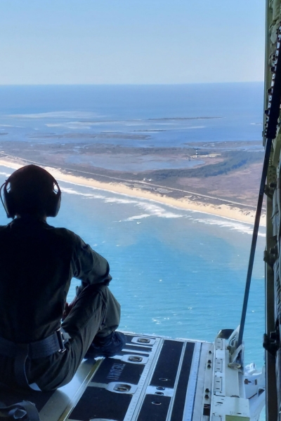 Cadet in the Coast Guard AUP looks out of the open back of a plane during training exercises.