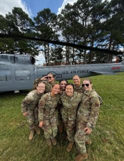 Air Force ROTC cadets pose for a photo in front of a helicopter during Field Training.