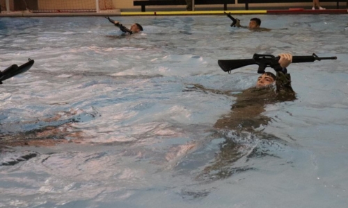 Army ROTC cadets hold rifles above water in a pool on campus, called Post at VMI, a military college in Virginia.