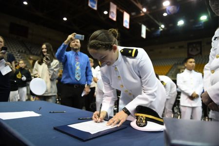 Female cadet from VMI signs commissioning paperwork for the US Navy following completion of her ROTC program.