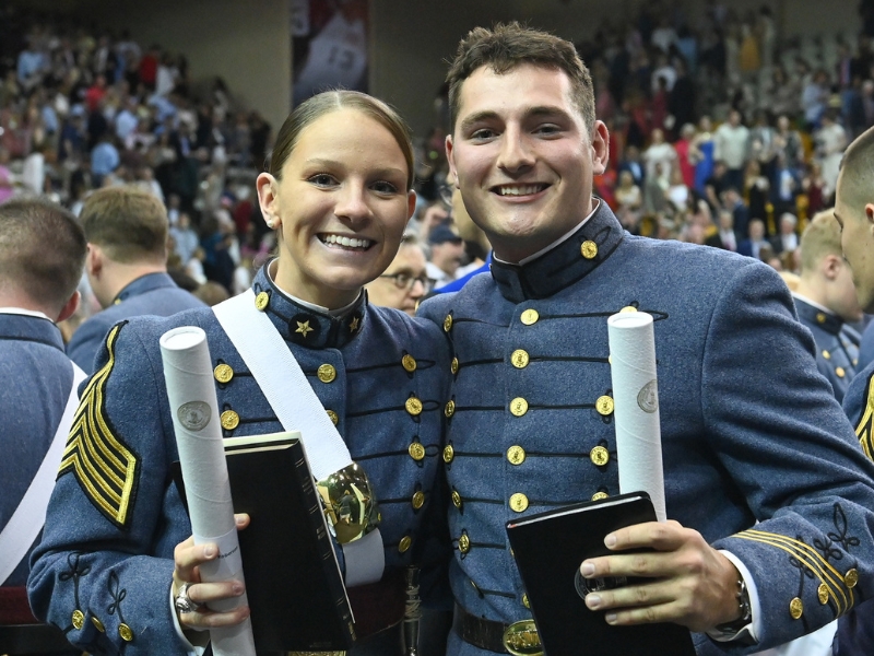 Two recent graduates of Virginia Military Institute pose with their diplomas after commencement.