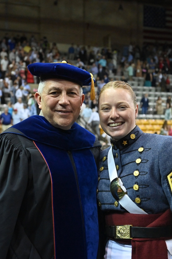 A recent graduate poses with the dean of academics at graduation.