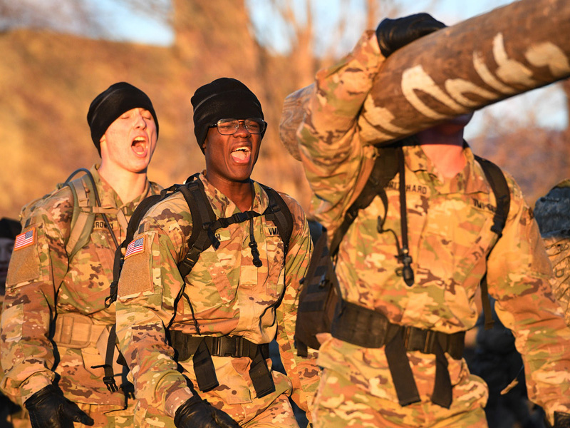 First year VMI cadets carrying logs in early morning sun during Break Out