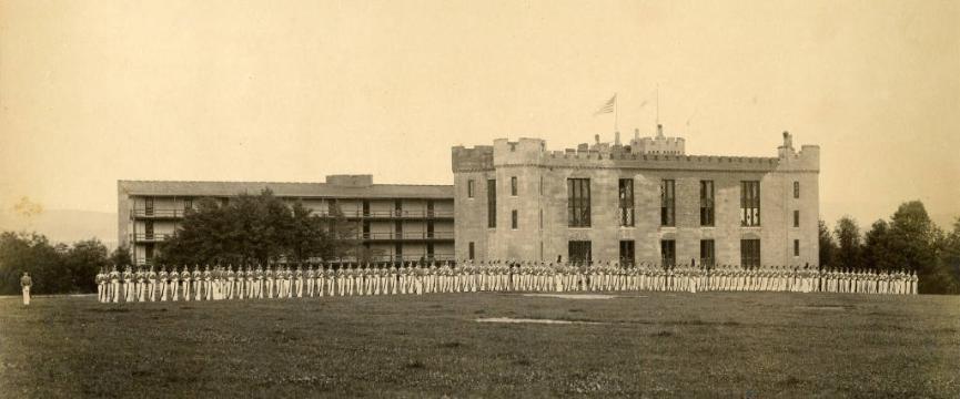 VMI barracks in the background with a line of cadets facing the camera in the foreground