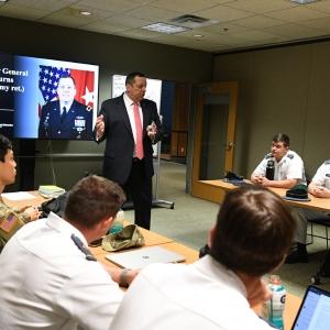 White male speaker talking to a room full of cadets