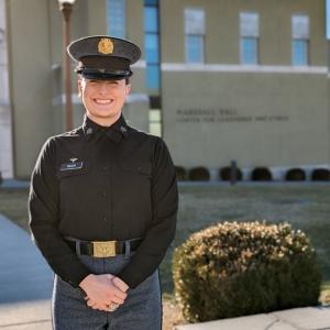 Cadet Kate Taylor in her winter class dyke uniform standing in front of Marshall Hall