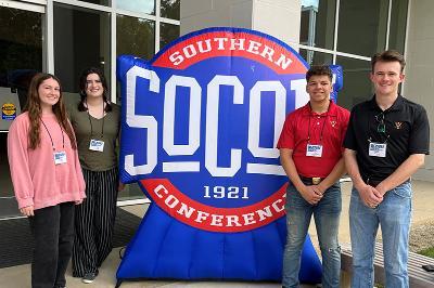 Cadets Davidson, Fernandez-Grimes, Handford and Osborne pose in front of the SoCon sign at their research event.