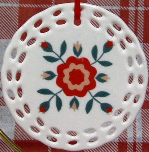 round 3 inch porcelain ornament with pierced edges and an image of the rose of Sharon pattern main large stylized rose with 8 small rose buds coming off main flower