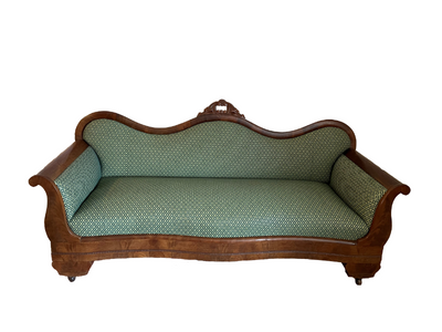 Short sofa with dark wood and green patterned upholstery, with a curved back.