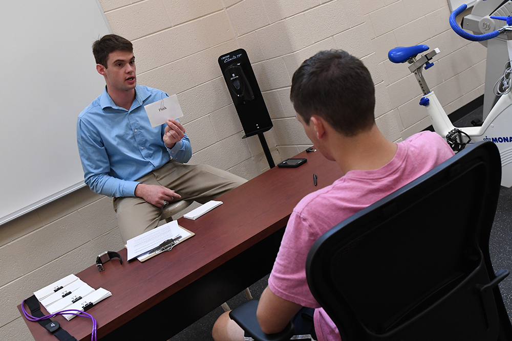 Cadet Sam Hudson show a flash card to a research subject.