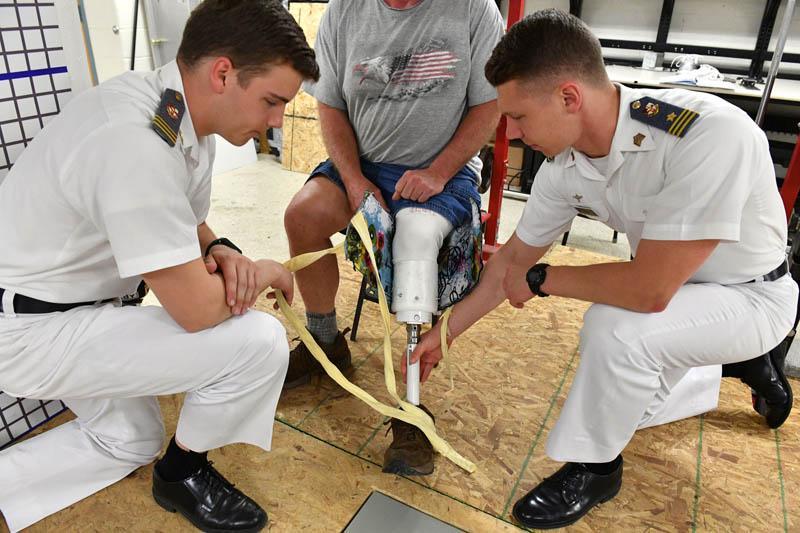 Spencer Jefferson ’17 and Philip Jewett ’17 fit the prosthetic leg they constructed as part of their capstone project onto a volunteer subject. – VMI Photo by Kelly Nye.