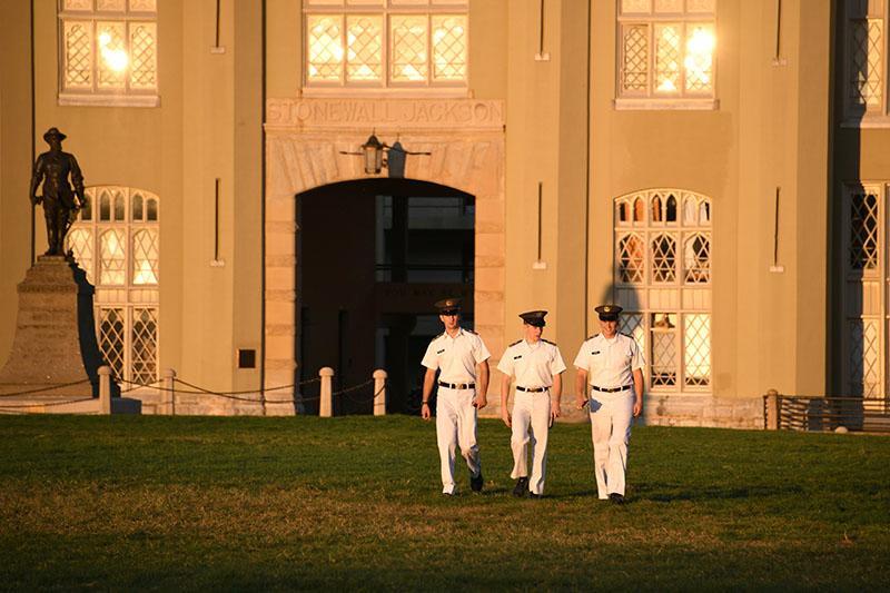Cadets walk across the parade ground in the evening.