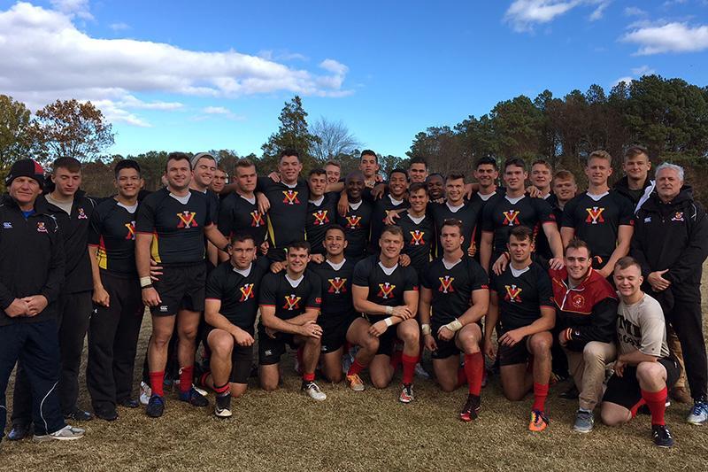 The rugby team gathers for a photo on the pitch.