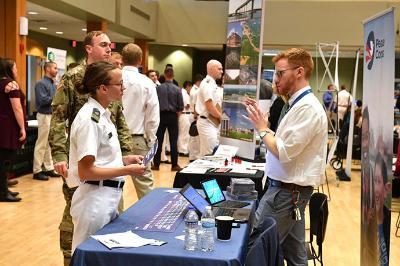 A female cadet talks with a representative from the Peace Corps during a career fair