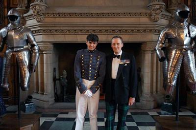 Milenski and Bailey standing in front of fireplace flanked by two suits of armor