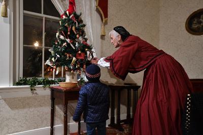Costumed interpreter with child at Christmas tree in Jackson House Museum.