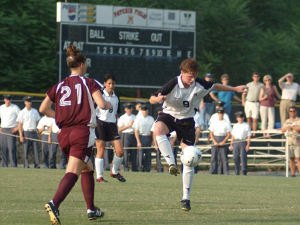 First VMI women's soccer match with player poised to kick the ball.