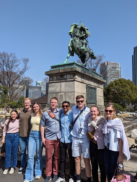 Eight college students pose in front of samurai statue during educational spring break trip to Japan.