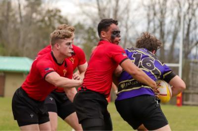 VMI rugby players tackle opponent.