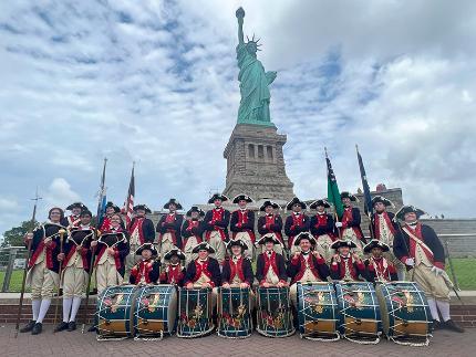 The Plymouth Fife and Drum Corps proudly stands at the base of the Statue of Liberty.