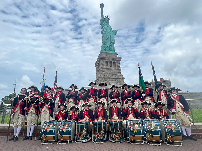 The Plymouth Fife and Drum Corps proudly stands at the base of the Statue of Liberty.