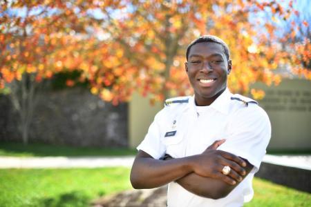 Maximus Ankrah poses outside on post near the George C. Marshall quote wall.