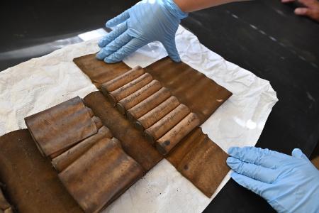 Moriah Delozier ’28 holds open the leather medical kit, displaying the sleeves holding the vials filled with compounds.