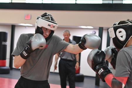 Capt. Jim Whitten observes as Andrew Kiddie ’29 spars with Dane Doucette ’29 during boxing class in Cormack Hall.