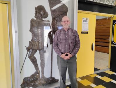 Col. Dan Barr ’74 stands beside the statue of conquistador, Juan Rodriguez Cabrillo, in the lobby of his alma mater, Cabrillo High School in Lompoc, California, after being inducted into the hall of fame.