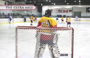 A goalie in front of a net on an ice rink.