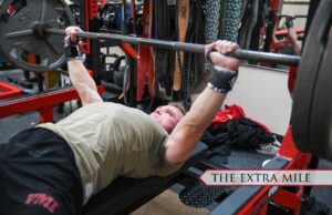 An athlete laying on a weight bench doing a bench press.