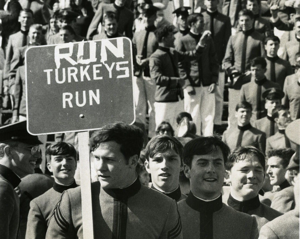 1974 VMI vs VPI football game, cadet carrying with sign reading “Run Turkeys Run"
