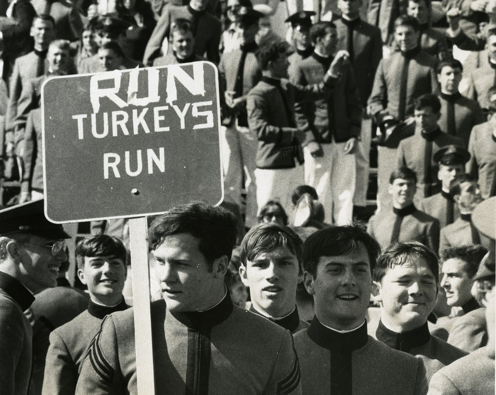 Cadets hold a Run Turkeys Run sign at a game in 1974.