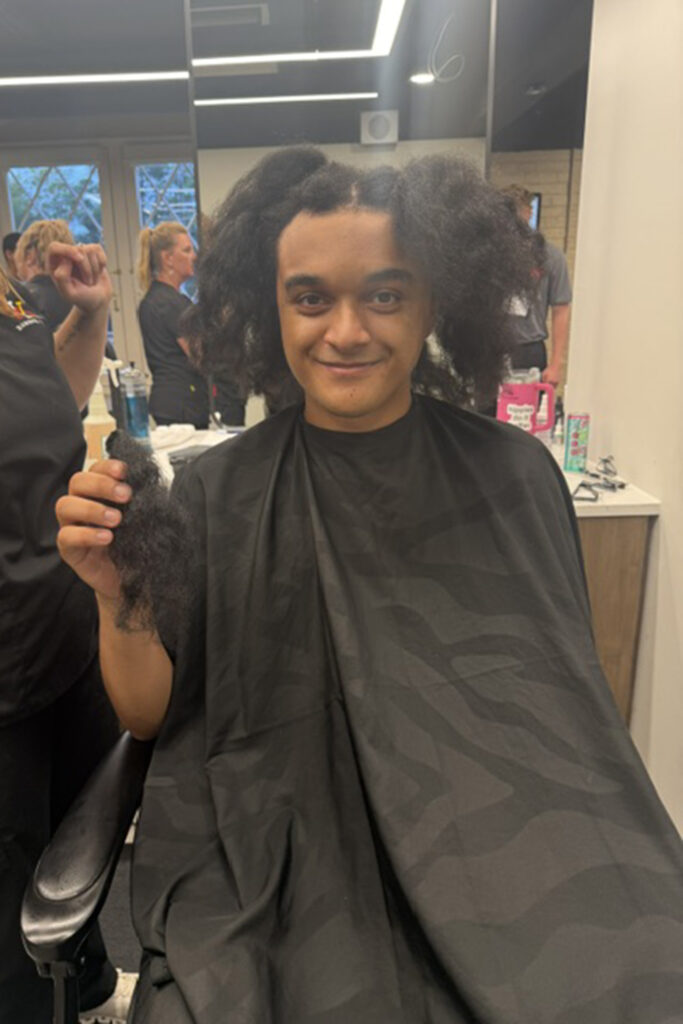 Leo Goyette holds a lock of his hair as a barber prepares to cut the rest. Goyette is donating his hair to an organization that makes wigs for children suffering from hair loss.