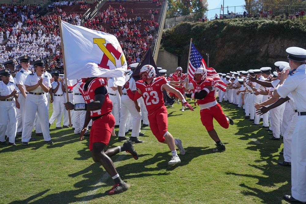 The football team runs into the stadium.